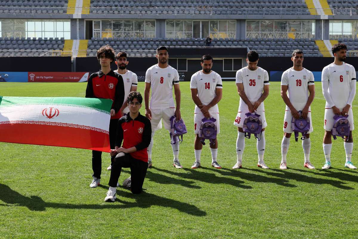 Jogadores iranianos prestam tributo a vítimas de escola básica segurando mochilas